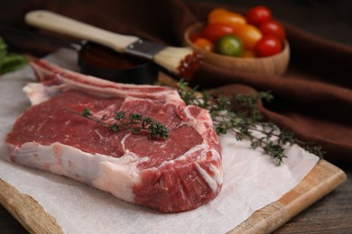 Photo of Raw meat and thyme on wooden table, closeup
