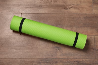 Bright rolled camping mat on wooden background, top view