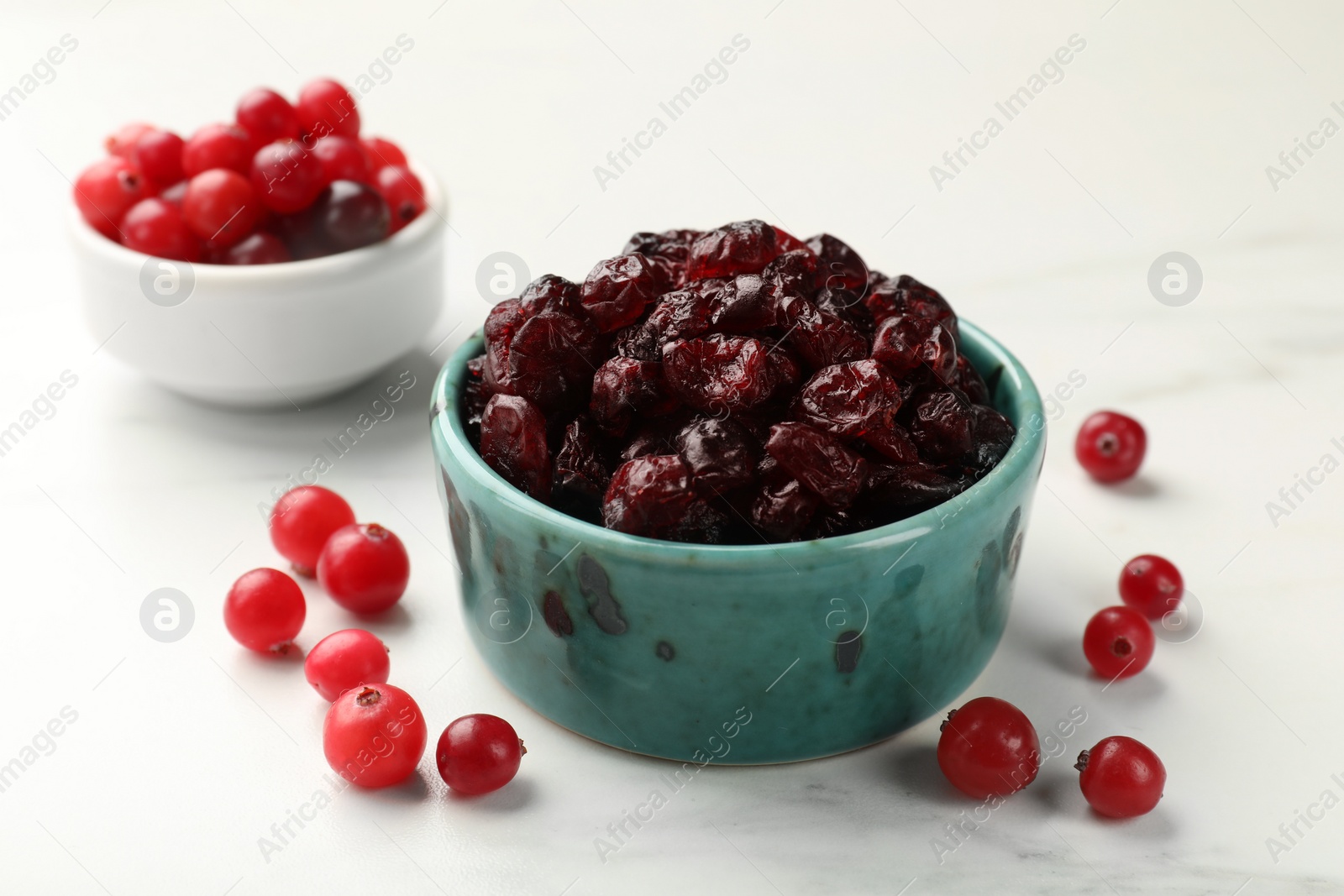 Photo of Tasty dried cranberries and fresh ones on white table, closeup