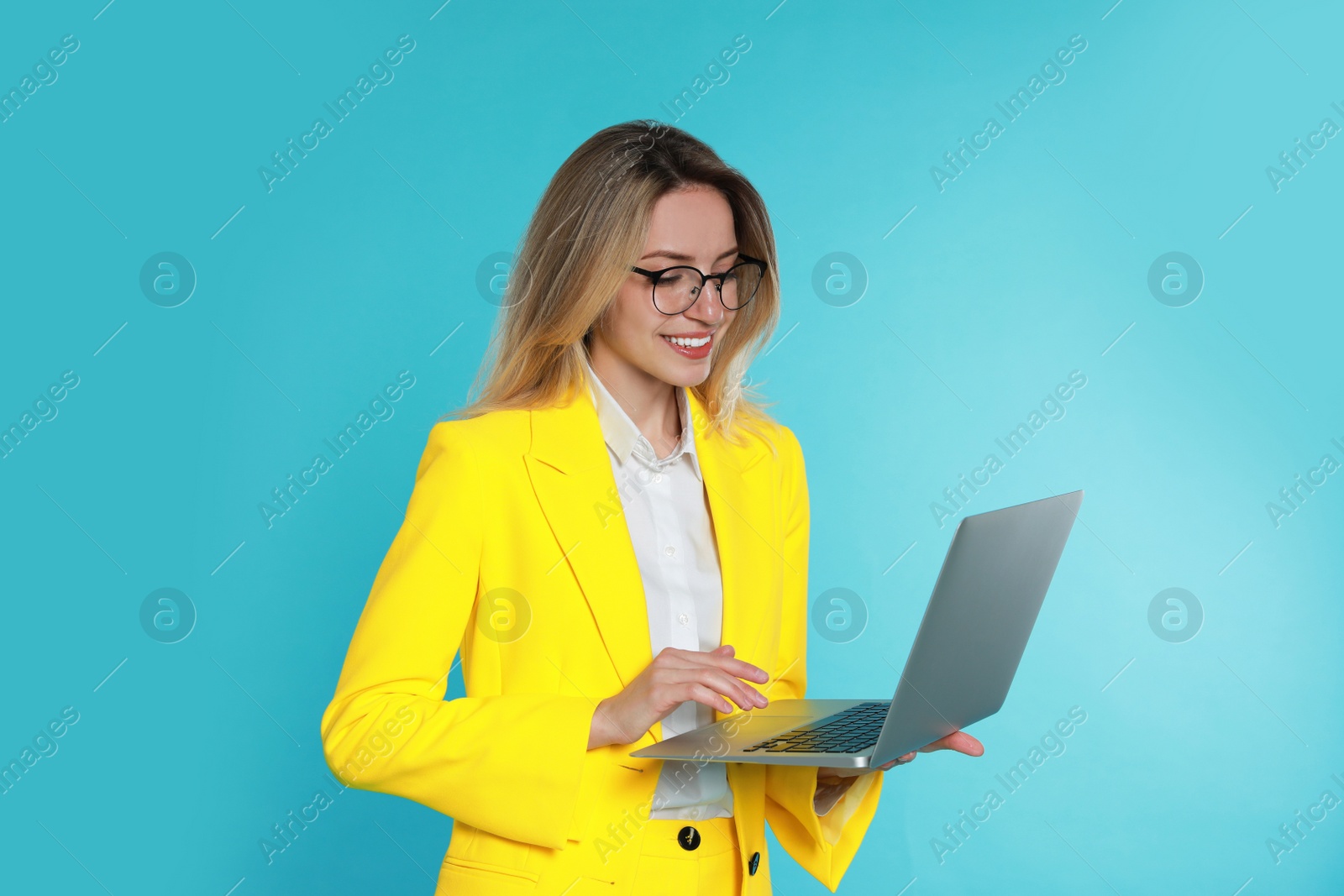 Photo of Young woman with modern laptop on light blue background