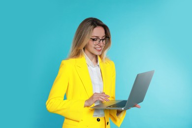 Young woman with modern laptop on light blue background