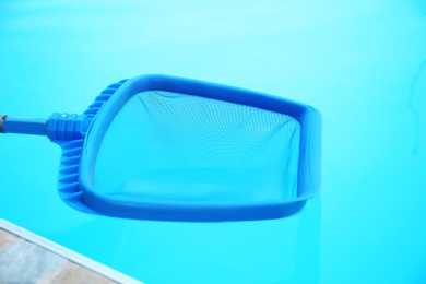 Photo of Cleaning outdoor pool with scoop net, closeup