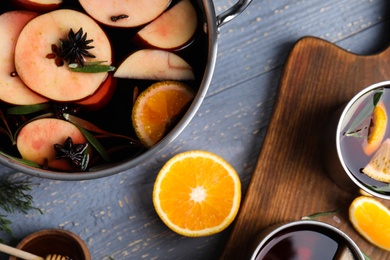 Photo of Tasty mulled wine with spices on grey wooden table, flat lay