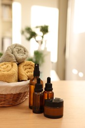 Photo of Bottles of essential oils, towels and jar with cream on wooden table indoors. Spa time