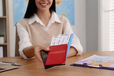 Travel agent with tickets and passports at table in office, closeup