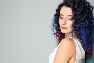 Photo of Young woman with bright dyed hair on light background, space for text