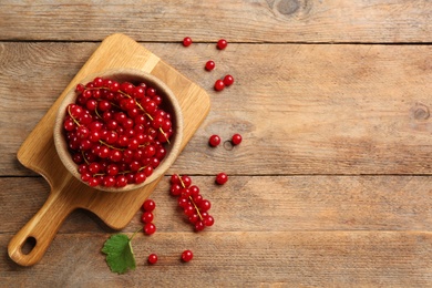 Photo of Delicious red currants on wooden table, flat lay. Space for text