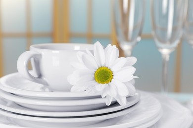 Photo of Set of clean dishware and flower on table, closeup