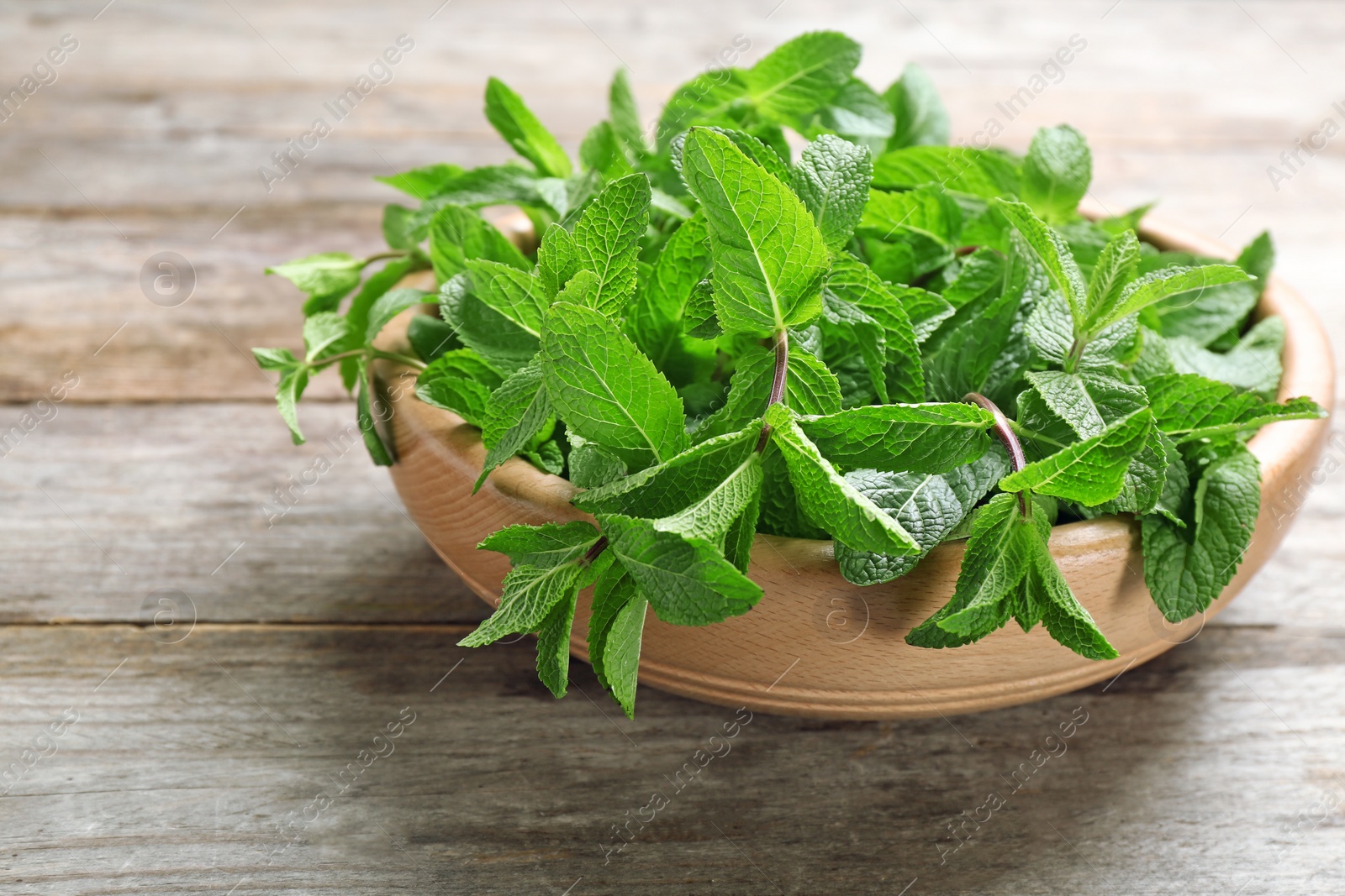 Photo of Bowl with fresh mint on wooden table