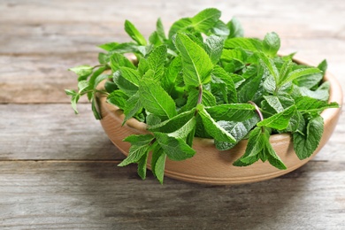 Photo of Bowl with fresh mint on wooden table