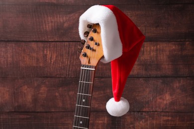 Guitar with cute Santa hat on wooden background. Christmas music