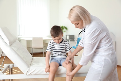 Photo of Doctor examining little patient with knee problem in clinic