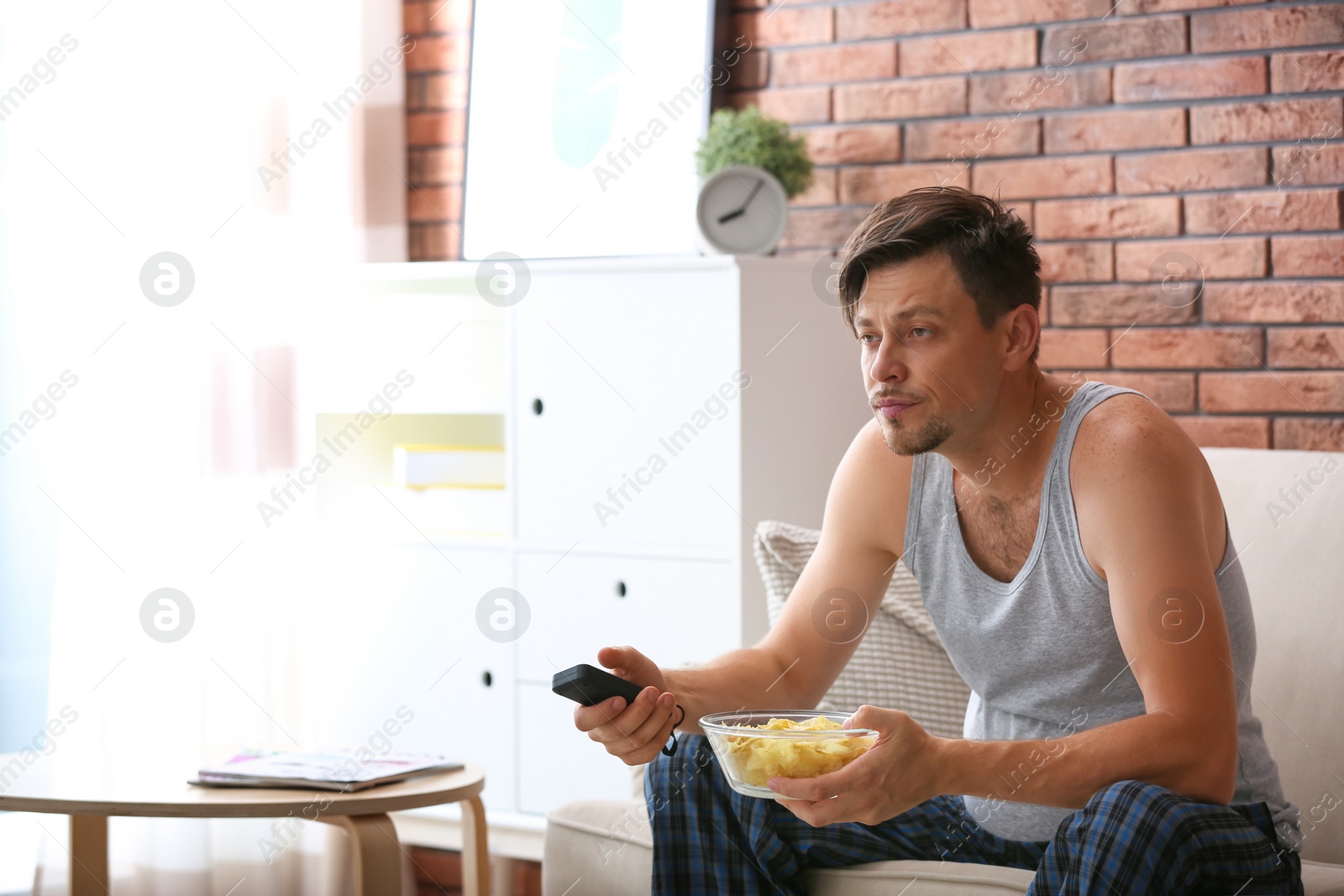 Photo of Lazy man with bowl of chips watching TV at home