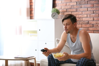 Lazy man with bowl of chips watching TV at home