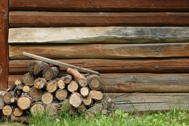 Photo of Pile of cut firewood near wooden wall on summer day, space for text