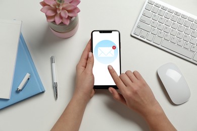 Image of Woman checking new message on mobile phone at table, top view