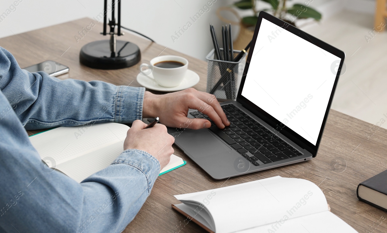 Photo of E-learning. Man using laptop during online lesson at table indoors, closeup