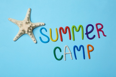 Photo of Text SUMMER CAMP made of modelling clay and starfish on color background, flat lay