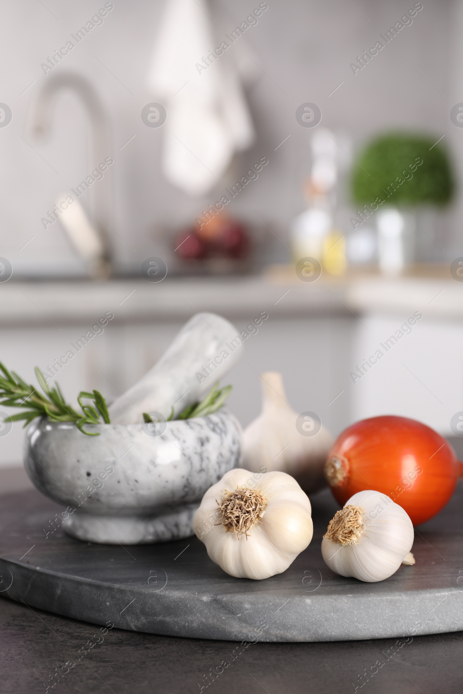Photo of Fresh raw garlic, onion and rosemary on grey table, closeup. Space for text