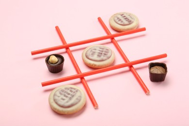 Photo of Tic tac toe game made with cookies and sweets on pink background