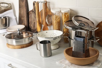 Photo of Different cooking utensils and raw pasta on countertop in kitchen