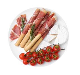 Plate of delicious grissini sticks with prosciutto, tomatoes and cheese on white background, top view
