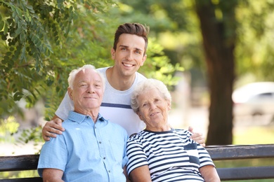 Man with elderly parents in park on sunny day