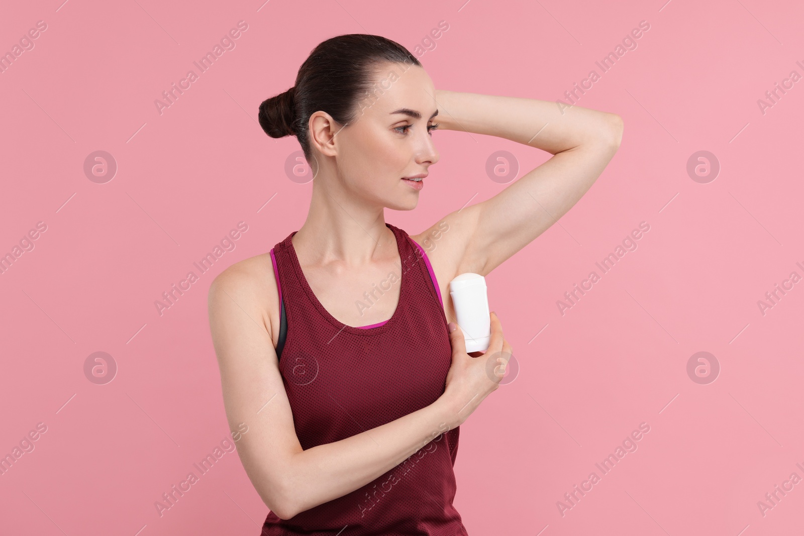 Photo of Beautiful woman applying deodorant on pink background