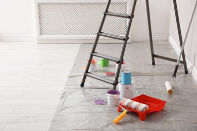 Different paints and decorator's tools near ladder indoors, space for text