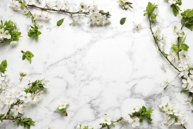 Photo of Frame of cherry tree branches with beautiful blossoms on white marble table, flat lay. Space for text