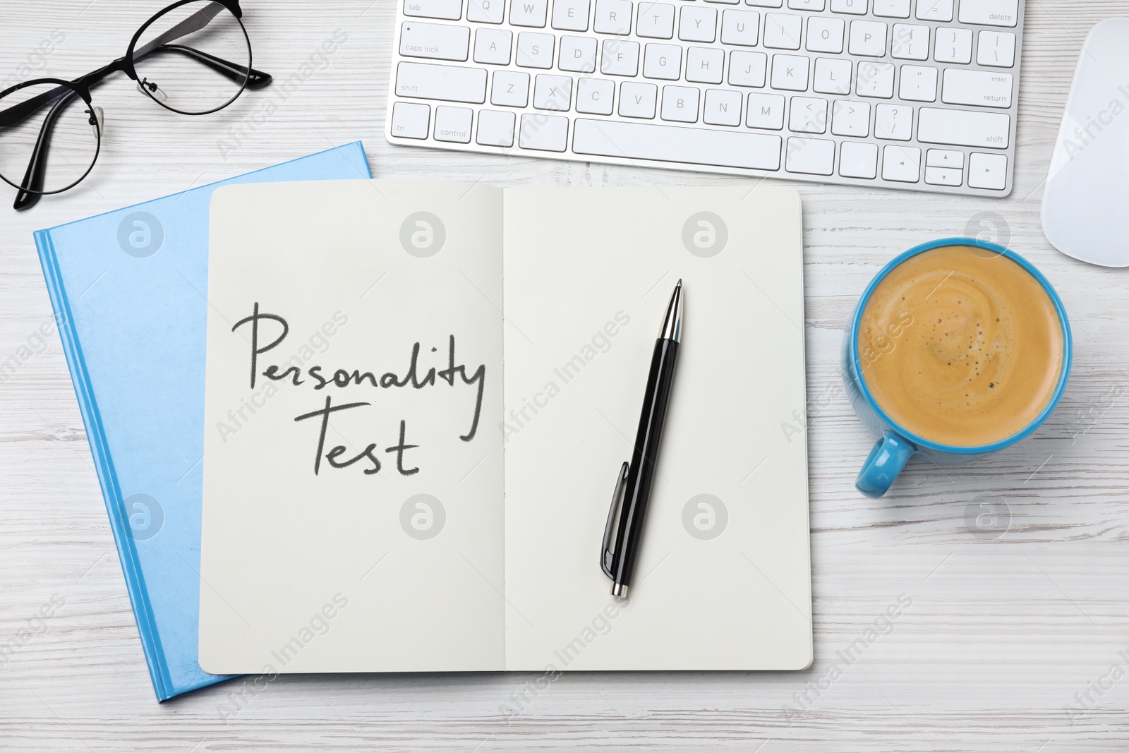 Image of Notebook with text Personality Test, computer keyboard and cup of coffee on white wooden desk, flat lay