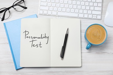 Image of Notebook with text Personality Test, computer keyboard and cup of coffee on white wooden desk, flat lay