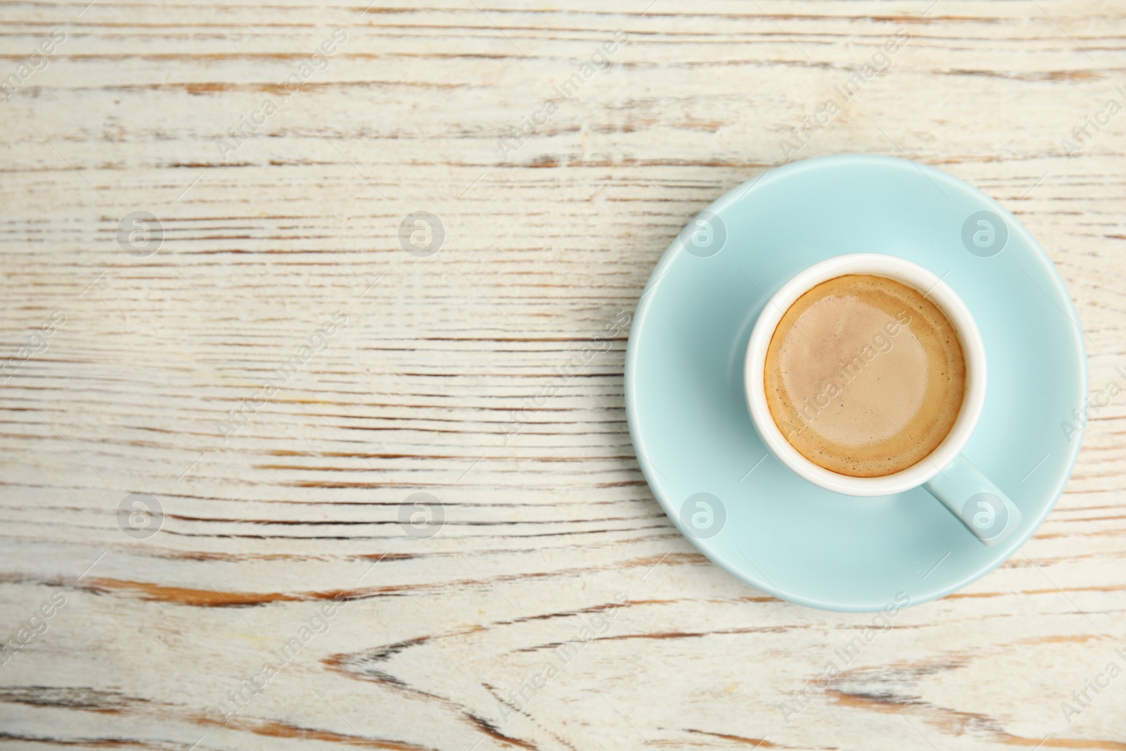 Photo of Cup of tasty coffee on white wooden table, top view. Space for text