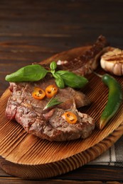 Photo of Delicious fried beef meat with garlic and chili pepper on wooden table