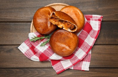 Photo of Delicious baked patties with cabbage and rosemary branches on wooden table, top view