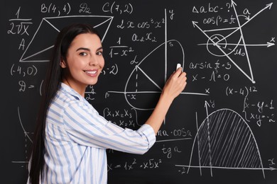 Photo of Happy teacher explaining mathematics at chalkboard in classroom