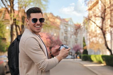 Happy male tourist with camera on city street