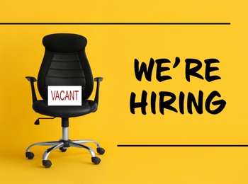 Image of Black office chair with sign VACANT and text WE`RE HIRING on yellow background