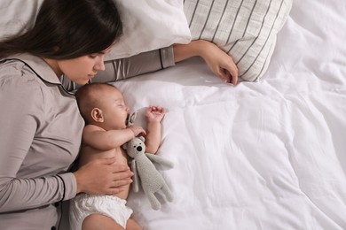 Photo of Mother and baby sleeping on bed together, top view. Space for text