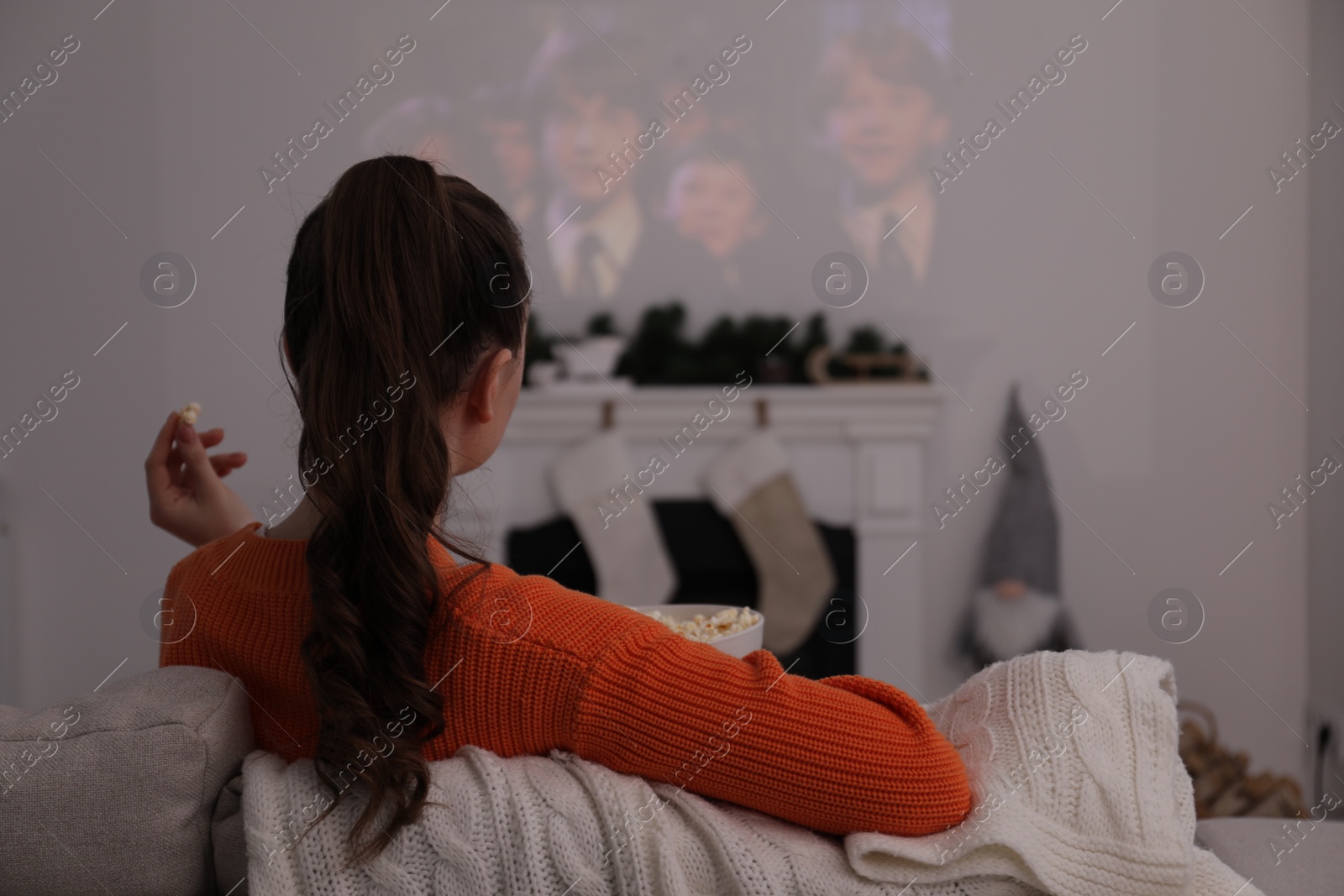 Photo of Lviv, Ukraine – January 24, 2023: Woman watching Harry Potter And The Philosopher’s Stone movie via video projector at home, back view