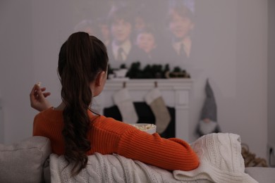 Lviv, Ukraine – January 24, 2023: Woman watching Harry Potter And The Philosopher’s Stone movie via video projector at home, back view