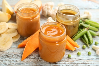 Jars with healthy baby food and ingredients on wooden table