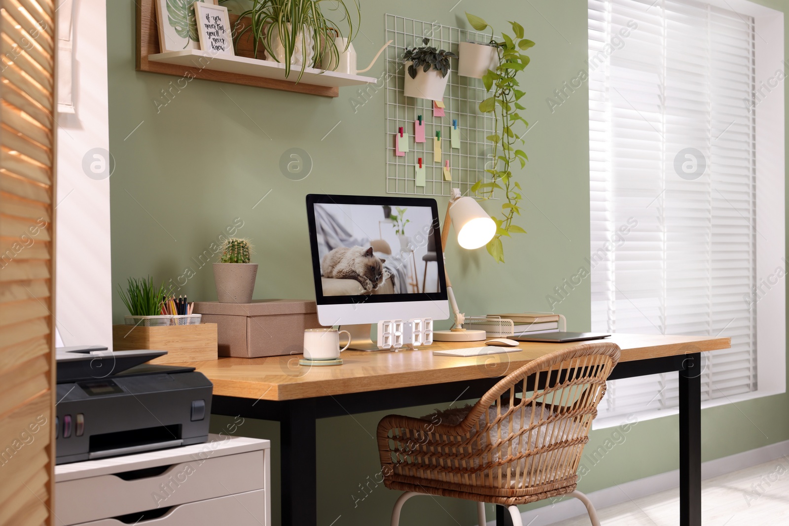 Photo of Stylish workplace with computer, laptop and lamp near olive wall at home