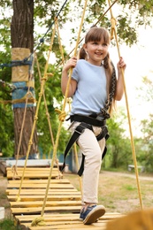 Little girl climbing in adventure park. Summer camp