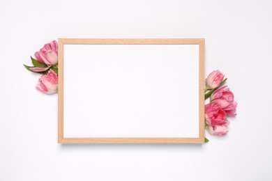 Photo of Empty photo frame and beautiful tulip flowers on white background, flat lay. Mockup for design