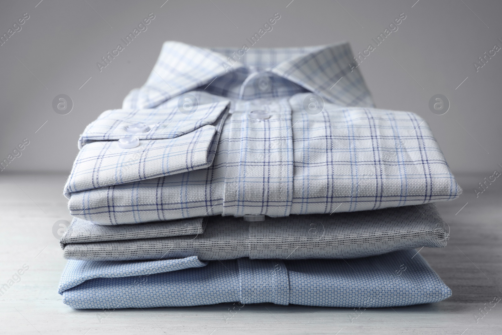 Photo of Stack of classic shirts on white wooden table