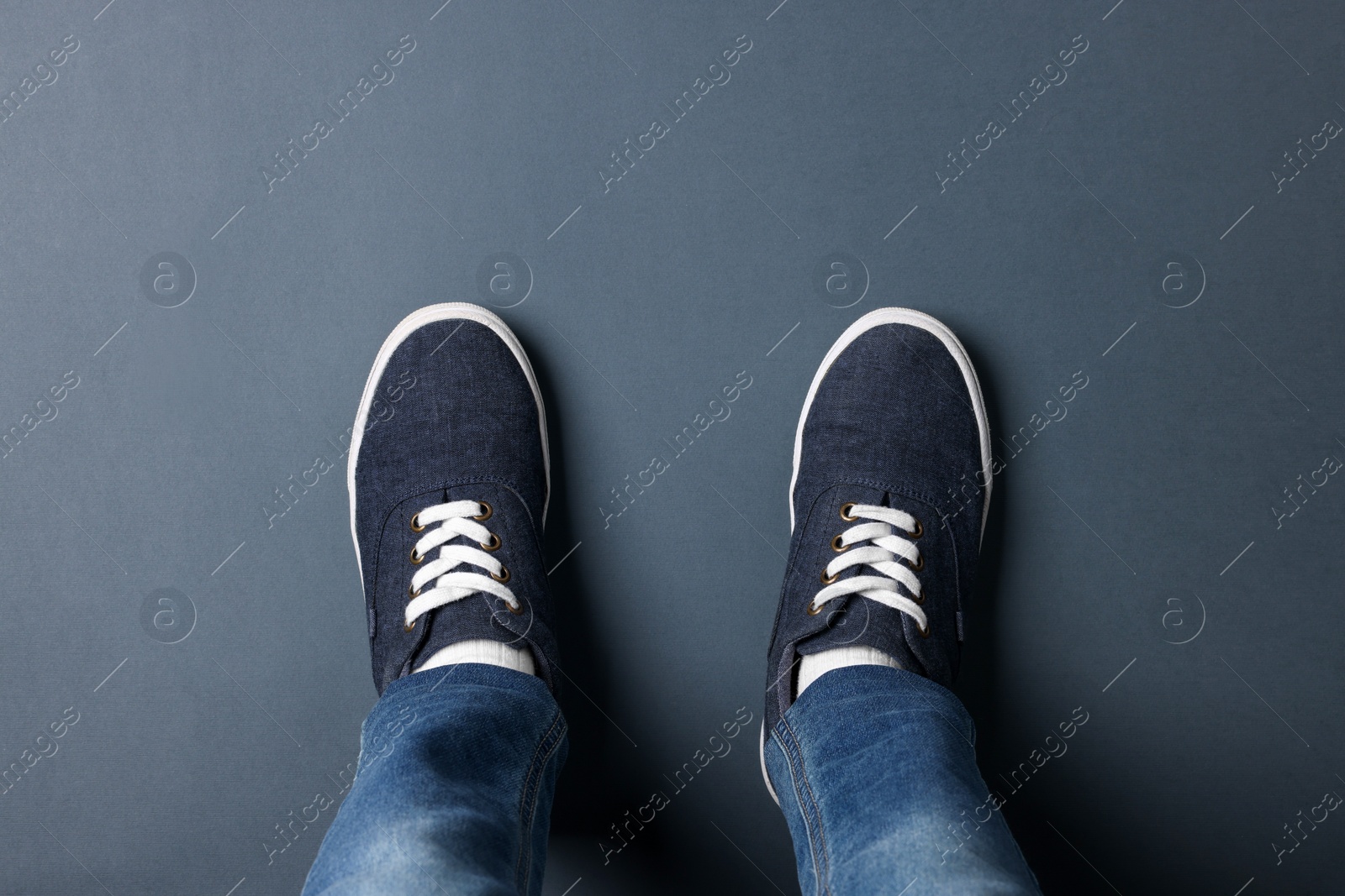 Photo of Child in stylish sneakers standing on grey background, top view