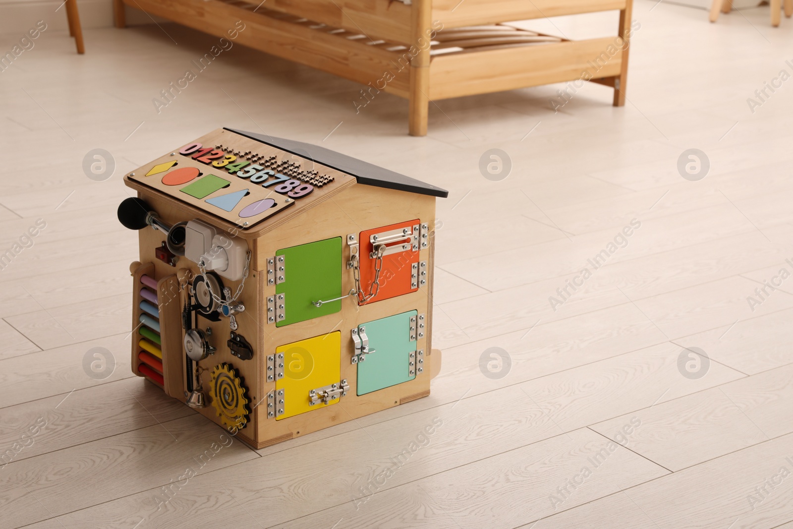 Photo of Busy board house on floor indoors, space for text. Baby sensory toy