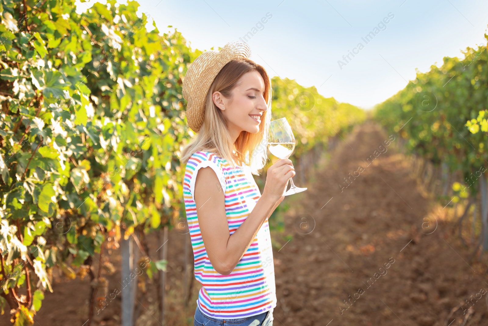 Photo of Young beautiful woman tasting wine at vineyard on sunny day