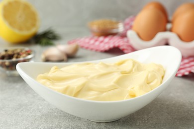 Photo of Delicious homemade mayonnaise near ingredients on grey table, closeup
